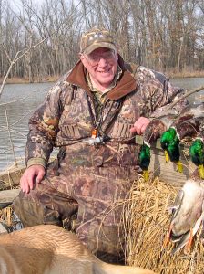 Jeff Churan posing with ducks and retriever