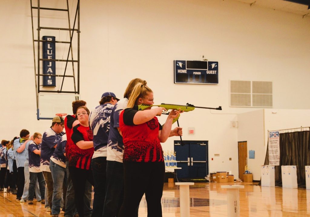 Student with Student Air Rifle Programs Shoots Air Rifle at Target in Gymnasium