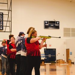 Student with Student Air Rifle Programs Shoots Air Rifle at Target in Gymnasium